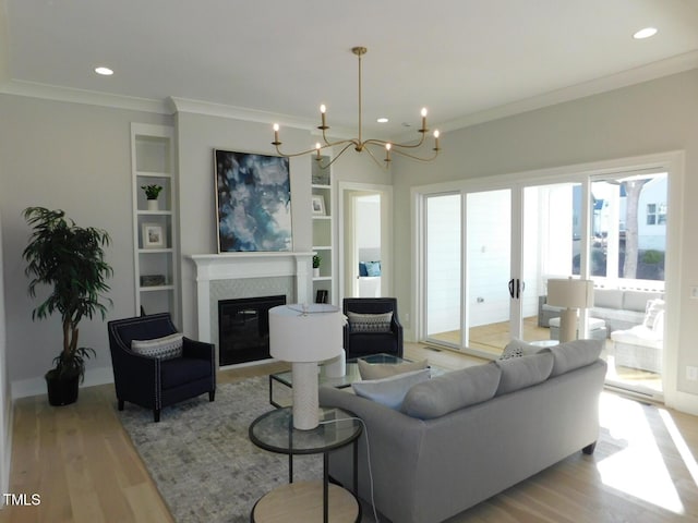 living room featuring ornamental molding, built in features, a chandelier, and light hardwood / wood-style flooring