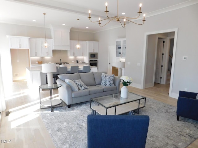 living room featuring crown molding, sink, and light wood-type flooring