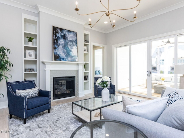 living area featuring built in shelves, light wood-type flooring, ornamental molding, and an inviting chandelier