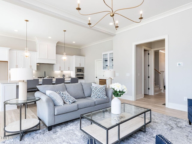 living area with ornamental molding, a notable chandelier, light wood finished floors, and stairs