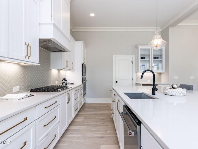 kitchen with glass insert cabinets, light countertops, a sink, and appliances with stainless steel finishes