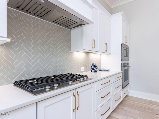 kitchen featuring white cabinetry, appliances with stainless steel finishes, custom exhaust hood, and light countertops