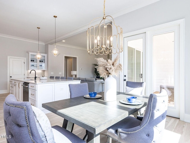 dining area with baseboards, ornamental molding, light wood-type flooring, and an inviting chandelier