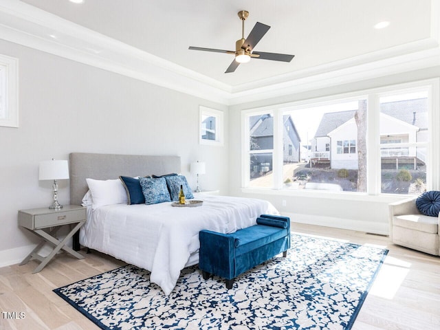 bedroom with baseboards, a raised ceiling, a ceiling fan, ornamental molding, and wood finished floors