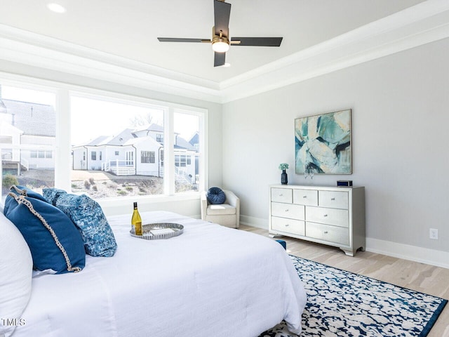 bedroom featuring ornamental molding, light wood-style flooring, baseboards, and a ceiling fan