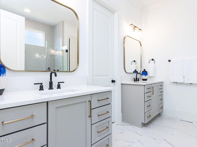 bathroom featuring visible vents, a sink, marble finish floor, a shower stall, and two vanities