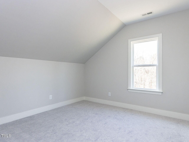 additional living space featuring baseboards, visible vents, vaulted ceiling, and carpet flooring