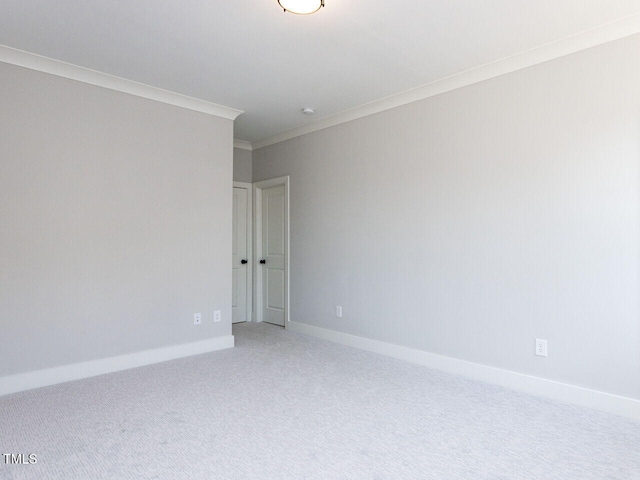 carpeted empty room featuring baseboards and crown molding