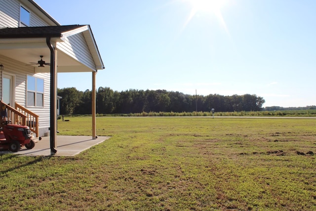 view of yard with a patio, ceiling fan, and a rural view