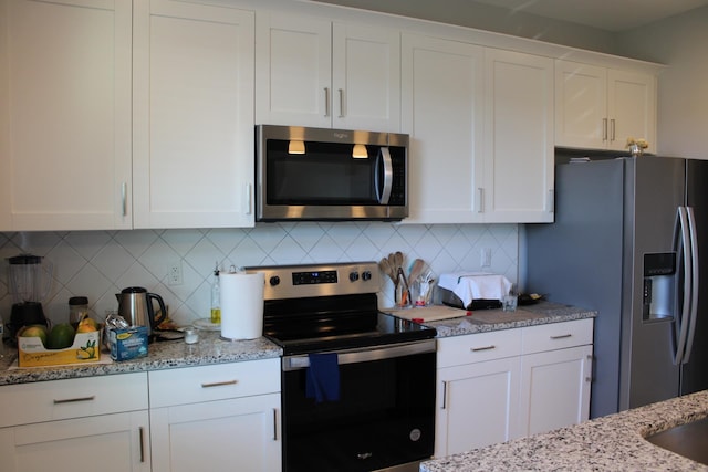 kitchen with backsplash, white cabinetry, appliances with stainless steel finishes, and light stone countertops