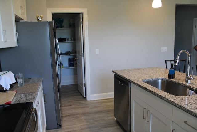 kitchen featuring light stone countertops, white cabinetry, dishwashing machine, sink, and light wood-type flooring