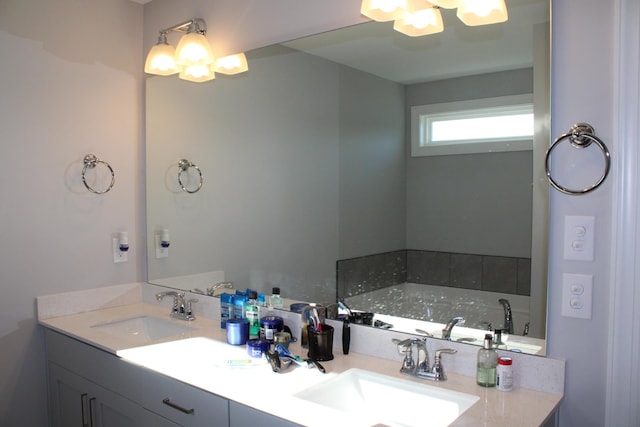 bathroom with dual sinks, oversized vanity, and a bath to relax in