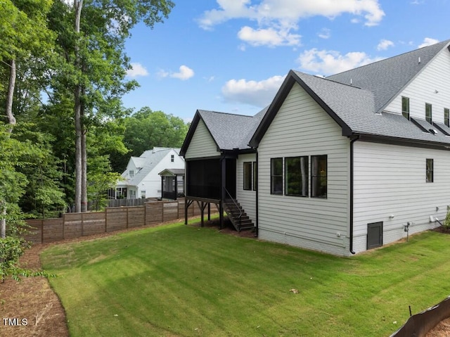 rear view of house featuring a lawn and a sunroom