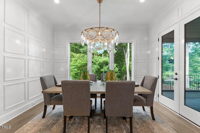 dining area with an inviting chandelier, wood-type flooring, crown molding, and french doors