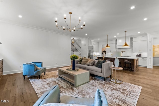 living room featuring light hardwood / wood-style floors, crown molding, and an inviting chandelier