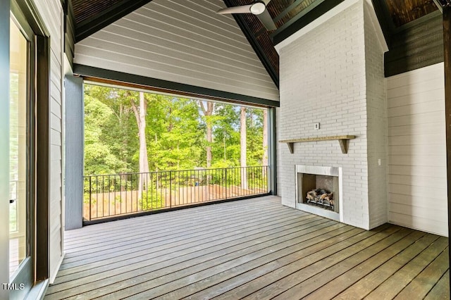 interior space featuring an outdoor brick fireplace, ceiling fan, and lofted ceiling