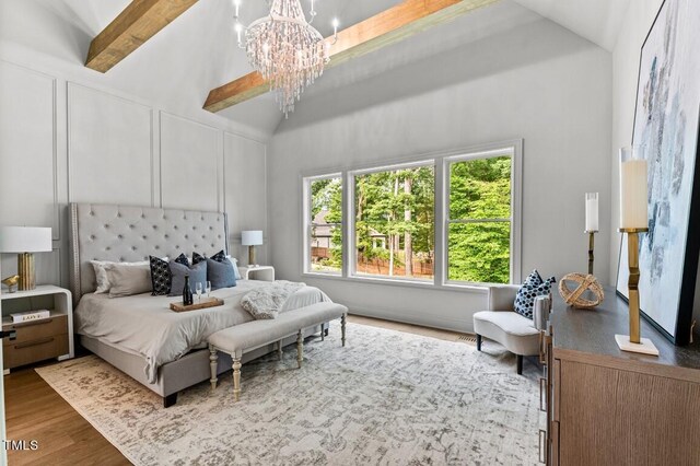 bedroom featuring beam ceiling, an inviting chandelier, hardwood / wood-style flooring, and high vaulted ceiling