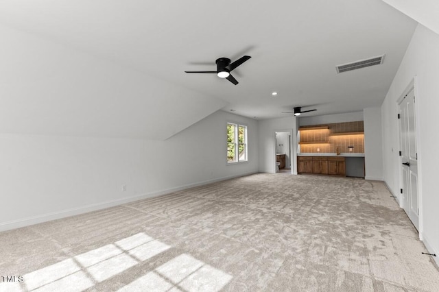 unfurnished living room with ceiling fan, light colored carpet, and vaulted ceiling