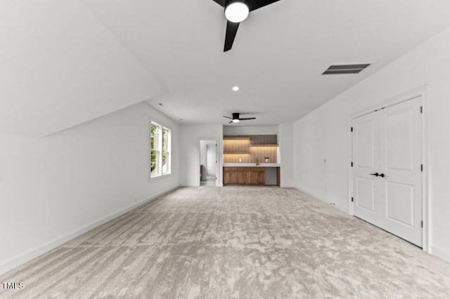 unfurnished living room with ceiling fan, light carpet, and lofted ceiling