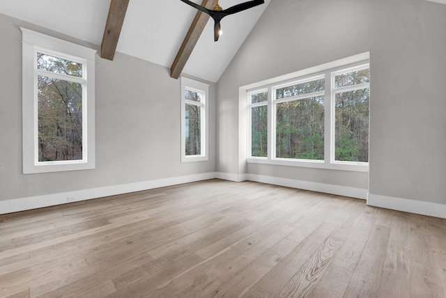 unfurnished room featuring ceiling fan, light wood-type flooring, beamed ceiling, and a wealth of natural light