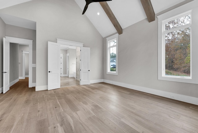 unfurnished bedroom with beam ceiling, high vaulted ceiling, light hardwood / wood-style floors, and multiple windows