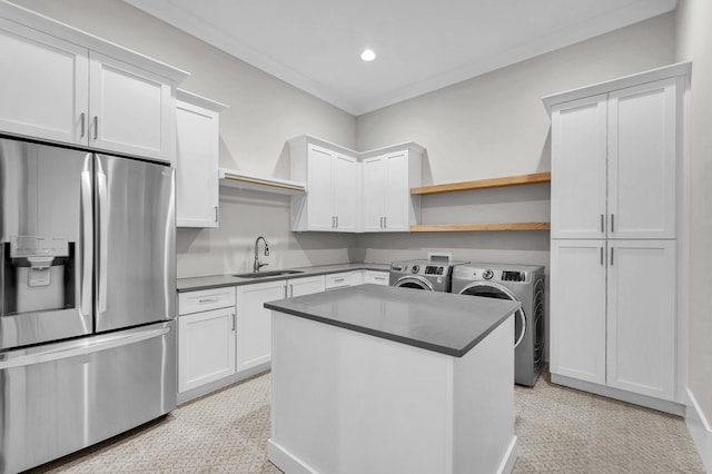 kitchen with white cabinetry, a center island with sink, stainless steel fridge with ice dispenser, sink, and washer and clothes dryer