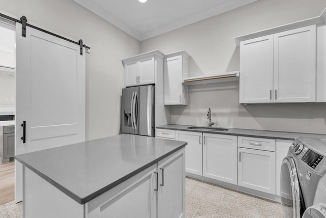 kitchen with white cabinetry, stainless steel fridge, a barn door, sink, and separate washer and dryer