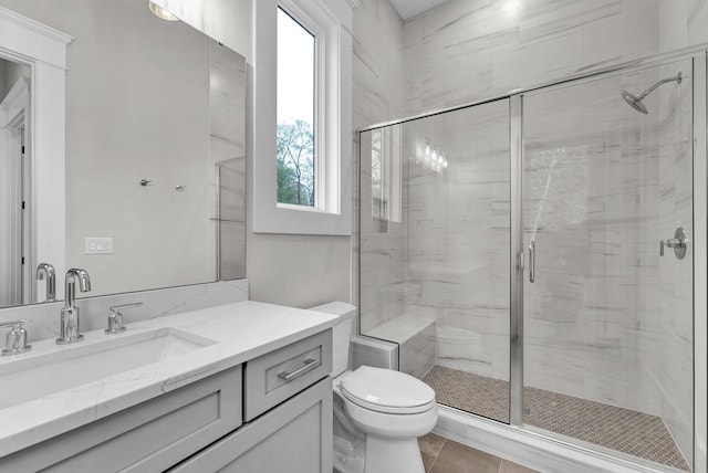 bathroom with toilet, tile flooring, a shower with shower door, and vanity