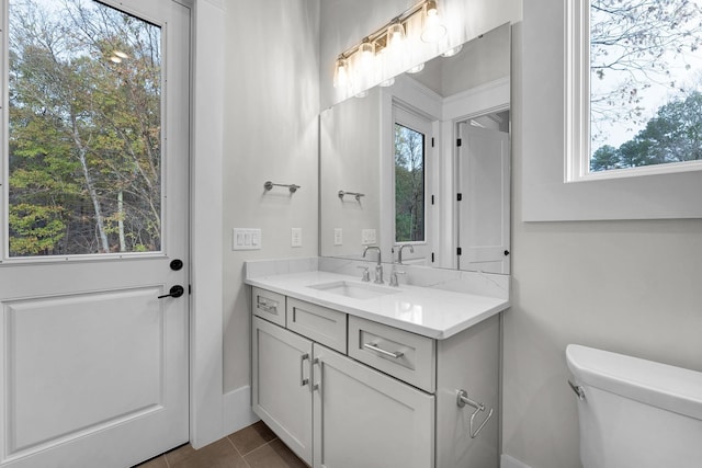 bathroom featuring tile flooring, toilet, and vanity with extensive cabinet space