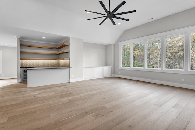 unfurnished living room featuring wine cooler, light hardwood / wood-style floors, ceiling fan, and vaulted ceiling