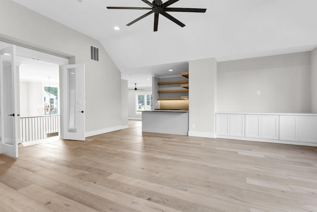 unfurnished living room with lofted ceiling, ceiling fan with notable chandelier, and light hardwood / wood-style flooring