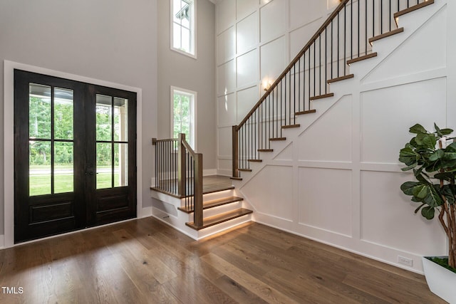 entrance foyer featuring french doors, dark hardwood / wood-style floors, and a towering ceiling