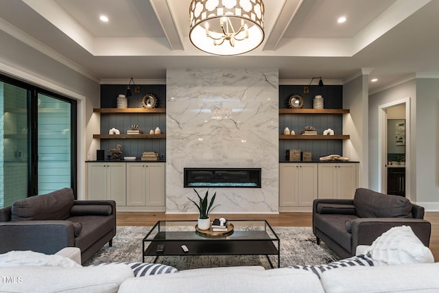 living room with ornamental molding, a tray ceiling, light wood-type flooring, and a fireplace