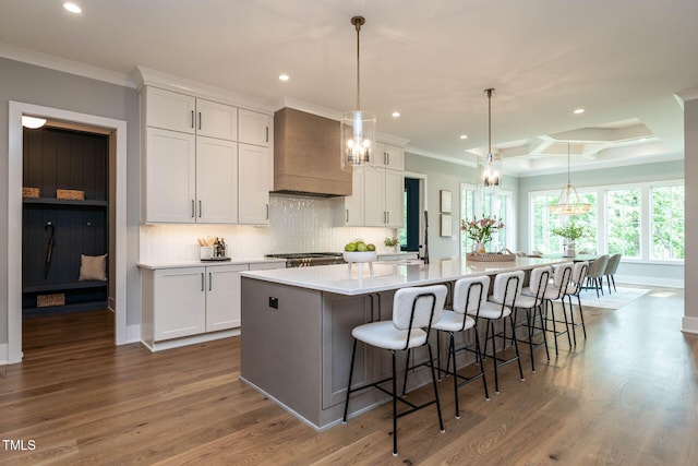 kitchen with a large island with sink, custom exhaust hood, white cabinetry, and hardwood / wood-style floors