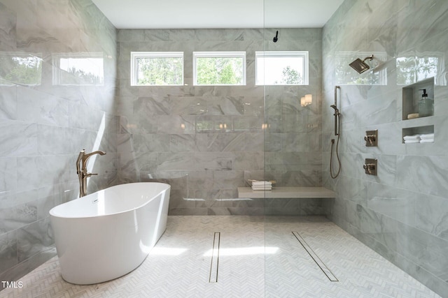 bathroom with a wealth of natural light, separate shower and tub, and tile walls