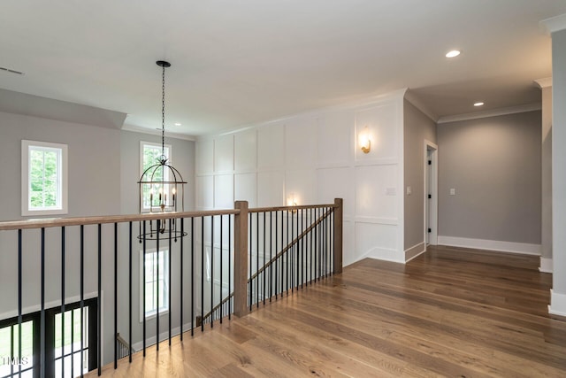 hall with ornamental molding, a notable chandelier, and wood-type flooring