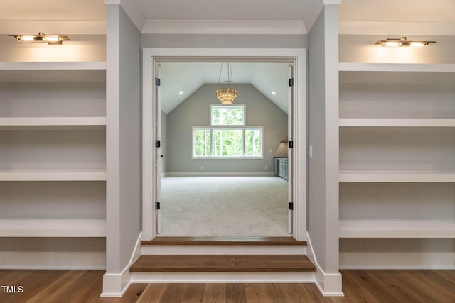 interior space with crown molding, built in features, vaulted ceiling, and hardwood / wood-style floors