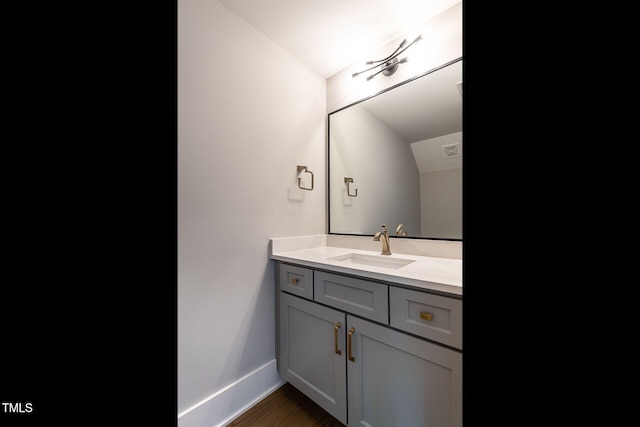 bathroom with vanity, hardwood / wood-style flooring, and lofted ceiling