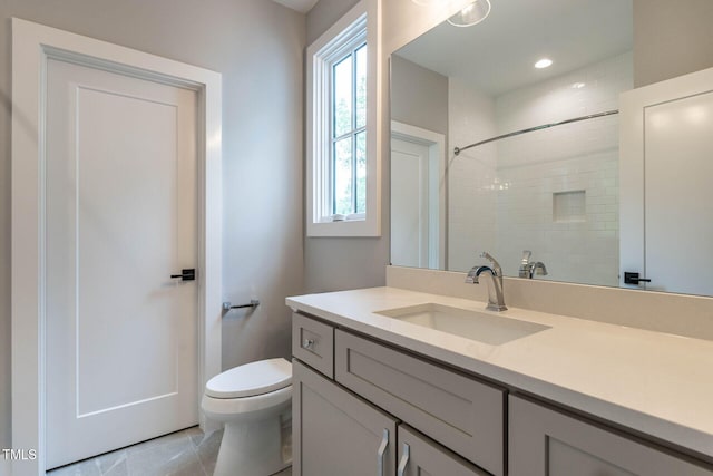 bathroom with vanity, tiled shower, toilet, and tile patterned floors