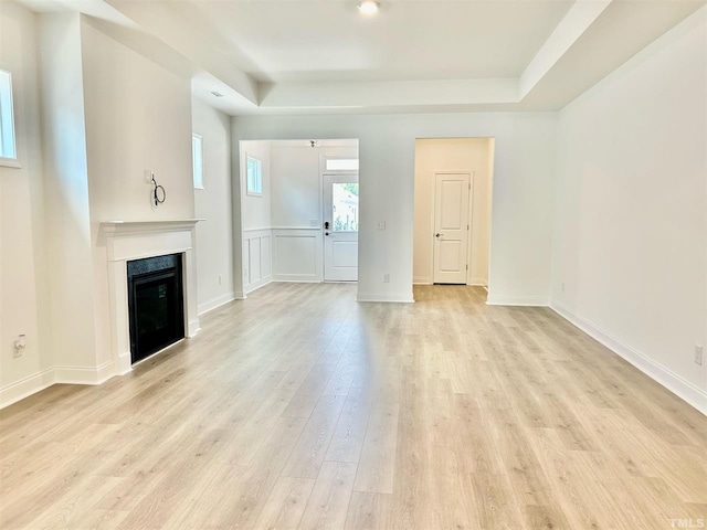 unfurnished living room with a raised ceiling and light hardwood / wood-style floors