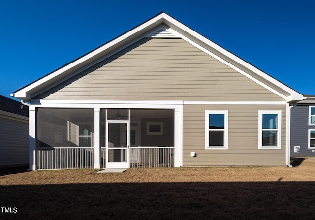 back of property with a yard and a sunroom