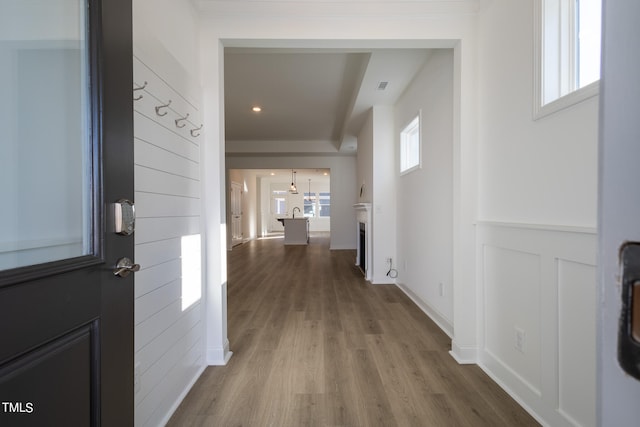 corridor with a wealth of natural light and hardwood / wood-style flooring