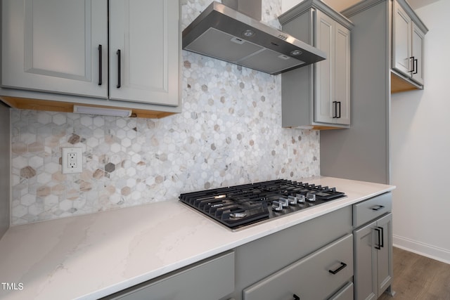 kitchen with wall chimney range hood, tasteful backsplash, gas cooktop, and dark hardwood / wood-style flooring