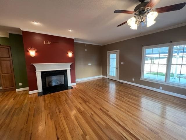 unfurnished living room with hardwood / wood-style floors, ceiling fan, and ornamental molding