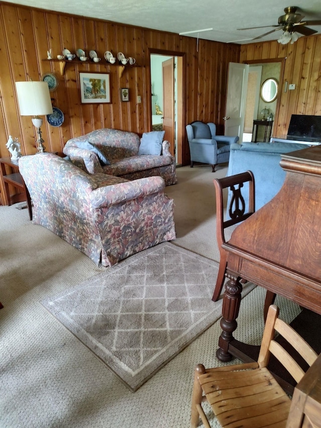 carpeted living room with ceiling fan and wooden walls