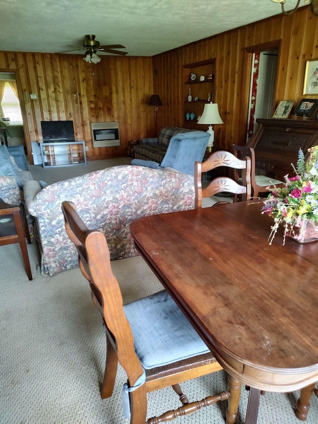 dining area featuring ceiling fan and wooden walls