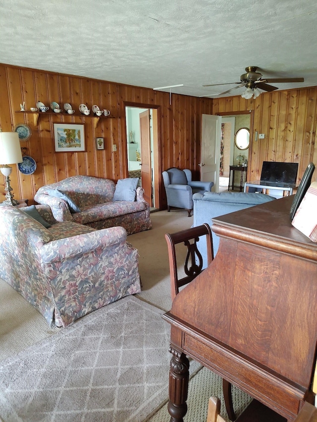 living room with wooden walls, ceiling fan, and carpet floors