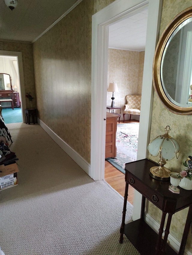 hall with ornamental molding and light hardwood / wood-style flooring