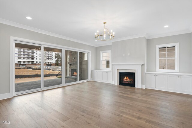 unfurnished living room with crown molding, a chandelier, and light hardwood / wood-style floors