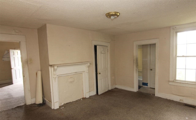 interior space featuring dark colored carpet and a textured ceiling